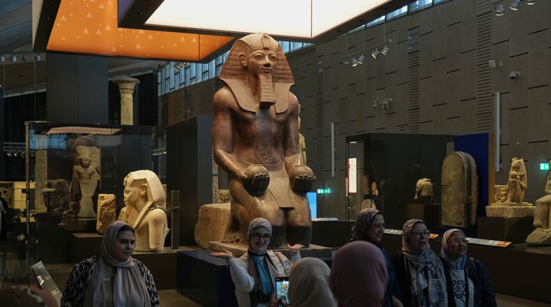Visitors pose for a group photo under Hatshepsut statue, at the Grand Egyptian Museum in Giza, Egypt, Friday, May 23, 2025. (AP Photo/Amr Nabil)