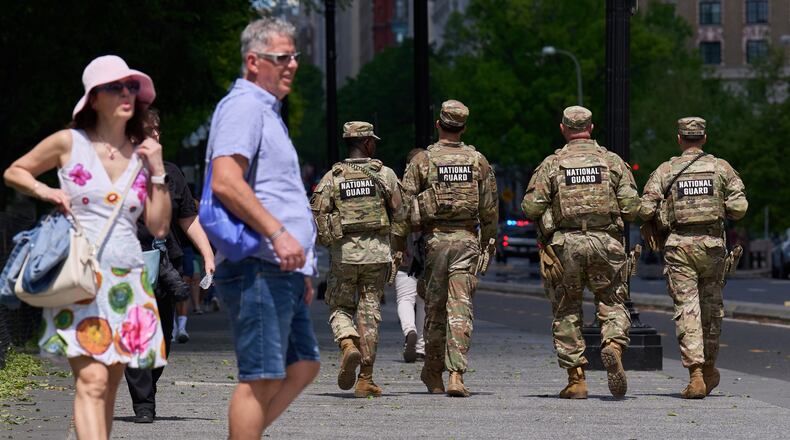 Members of the Florida National Guard pass by tourists on a sidewalk Friday April 17, 2026, in Washington. (AP Photo/Jacquelyn Martin)