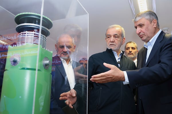 In this photo released by the Iranian Presidency Office, President Masoud Pezeshkian, second right, listens to head of Atomic Energy Organization of Iran Mohammad Eslami as he visits an exhibition of Iran's nuclear achievements, in Tehran, Iran, Wednesday, April 9, 2025. (Iranian Presidency Office via AP)