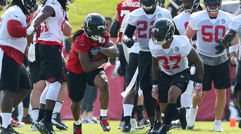 July 27, 2017 Flowery Branch: Falcons running back Devonta Freeman is surrounded by white defensive jersey as he hits a hole for yardage on the first day of team practice at training camp on Thursday, July 27, 2017, in Flowery Branch. Curtis Compton/ccompton@ajc.com