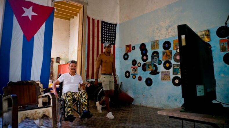 A U.S. and a Cuban flag hang from the wall of the home of Armando Ricart, a former boxer, carpenter and actor while he watches President Donald Trump's inauguration speech on television, in Havana, Cuba, Friday, Jan. 20, 2017. Donald Trump became the 45th president of the United States Friday, Jan. 20 2017, amid apprehension in Cuba regarding his campaign remarks on U.S. - Cuba relations. (AP Photo/Ramon Espinosa)
