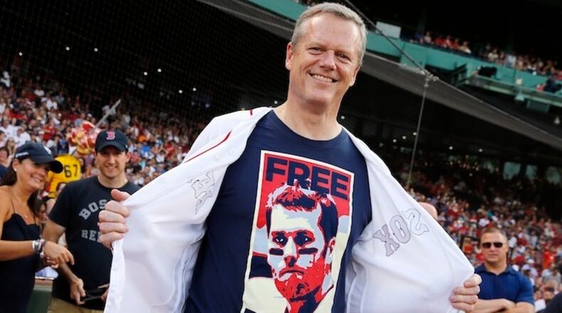 Massachusetts Gov. Charlie Baker displays a "Free Brady" T-shirt, in protest of New England Patriots quarterback Tom Brady's four-game suspension, before throwing out the ceremonial first pitch before a baseball game between the Boston Red Sox and the Minnesota Twins in Boston, Saturday, July 23, 2016. (AP Photo/Michael Dwyer)