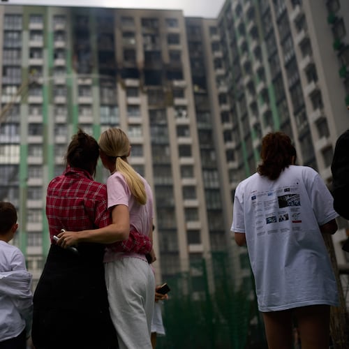 Locals watch as firefighters work after a Russian drone attack struck a residential building in Kyiv, Tuesday, Sept. 1, 2026. (AP Photo/Francisco Seco)