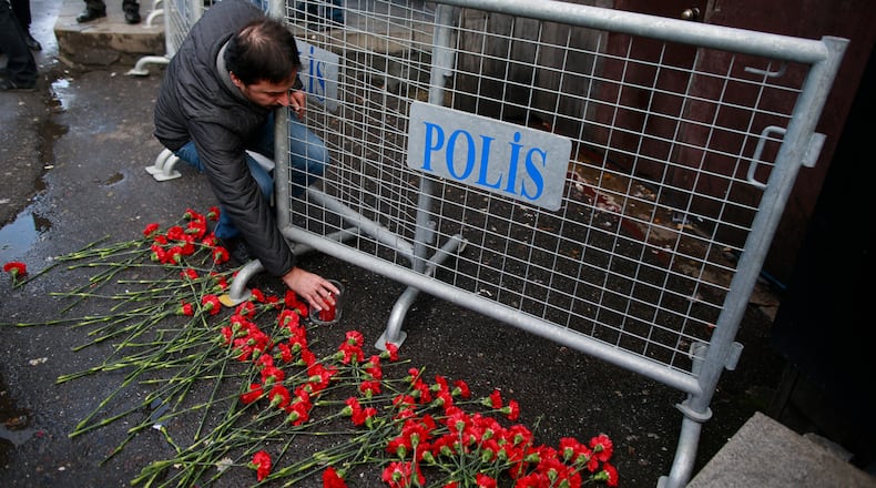 People leave flowers for the victims outside a a nightclub which was attacked by a gunman overnight, in Istanbul, on New Year's Day, Sunday, Jan. 1, 2017. An assailant believed to have been dressed in a Santa Claus costume and armed with a long-barrelled weapon, opened fire at the nightclub in Istanbul's Ortakoy district during New Year's celebrations, killing dozens of people and wounding dozens of others in what the province's governor described as a terror attack. (AP Photo/Emrah Gurel)