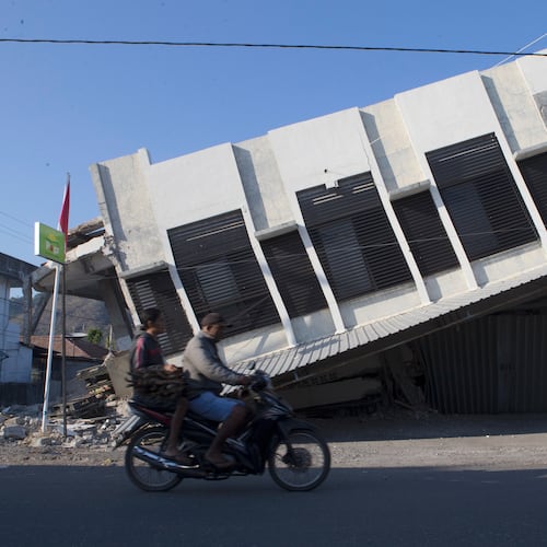 Motorists ride past a building that collapsed during an earthquake in Reo, East Nusa Tenggara province, Indonesia, Monday, Aug. 17, 2026. (AP Photo/Firdia Lisnawati)