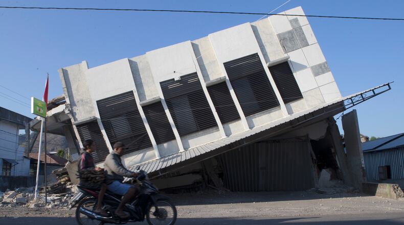Motorists ride past a building that collapsed during an earthquake in Reo, East Nusa Tenggara province, Indonesia, Monday, Aug. 17, 2026. (AP Photo/Firdia Lisnawati)