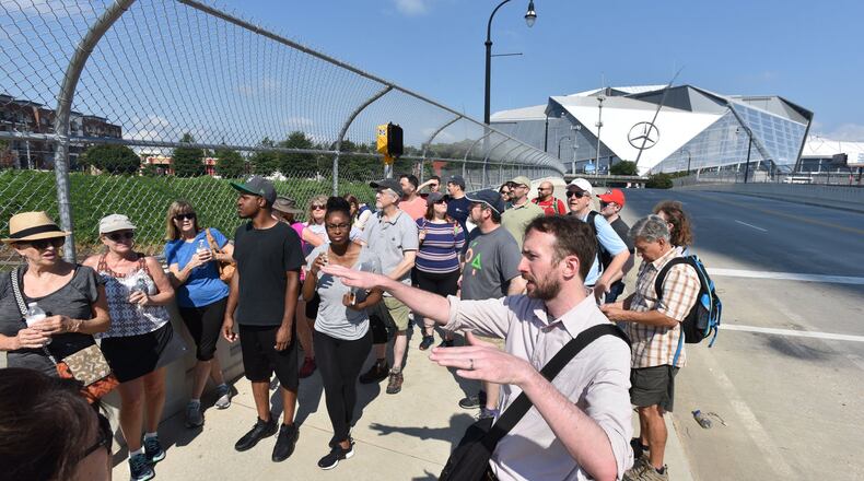 Kyle Kessler, community program manager of Center for Civic Innovation, leads a tour group near Mercedes-Benz Stadium on a south Downtown / Underground Atlanta Walking Tour on Saturday, August 5, 2017. HYOSUB SHIN / HSHIN@AJC.COM