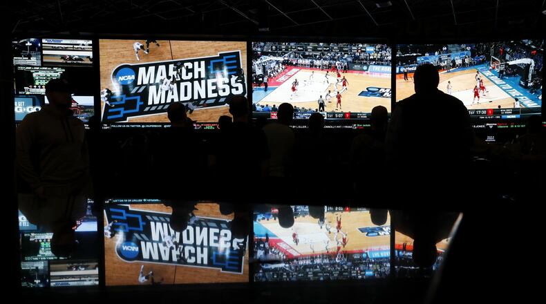 People watch coverage of the first round of the NCAA college basketball tournament at the Westgate Superbook sports book in Las Vegas. The Supreme Court in 2018 struck down a federal law that bars gambling on football, basketball, baseball and other sports in most states, giving states the go-ahead to legalize betting on sports. Georgia is considering such a measure. (AP Photo/John Locher)