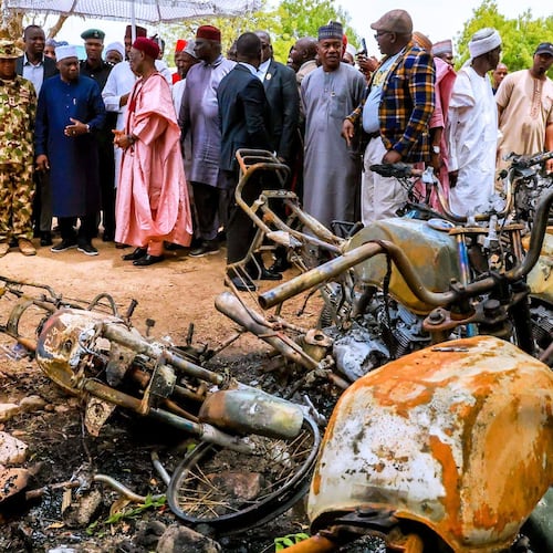 In this photo, released by Adamawa State Government House, Adamawa State Governor Ahmadu Umaru Fintiri, left white hat, inspects an area in Guyaku, northeastern Nigeria, Monday, April 27, 2026, that was attacked by Militants with the Islamic State group on Sunday. (Adamawa state government house via AP)
