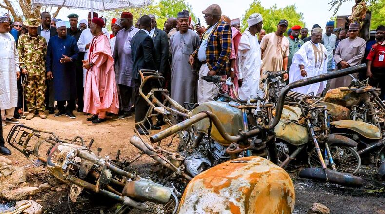 In this photo, released by Adamawa State Government House, Adamawa State Governor Ahmadu Umaru Fintiri, left white hat, inspects an area in Guyaku, northeastern Nigeria, Monday, April 27, 2026, that was attacked by Militants with the Islamic State group on Sunday. (Adamawa state government house via AP)