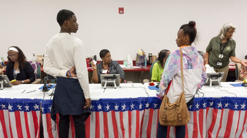 Jeremiah Culver, left, and Quinnayah Durden, right, both seniors at Columbia High School, wait to have their voting paperwork processed in Atlanta, on Monday, October 31, 2016. (DAVID BARNES / DAVID.BARNES@AJC.COM)