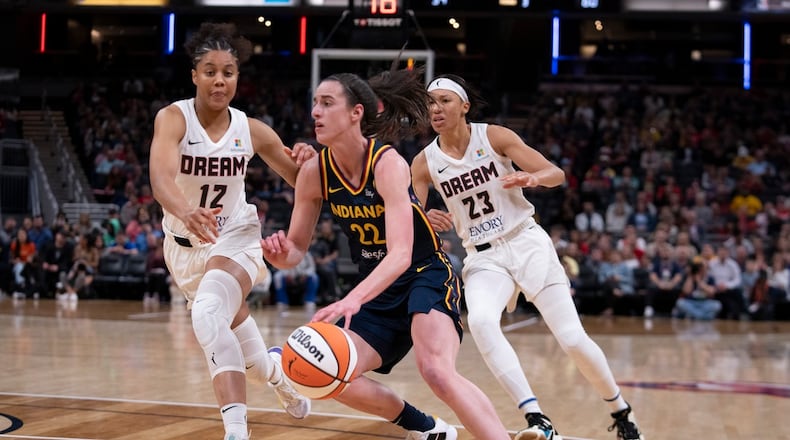 Indiana Fever's Caitlin Clark (22) goes to the basket against Atlanta Dream's Nia Coffey (12) and Aerial Powers (23) during the second half of a WNBA preseason basketball game Thursday, May 9, 2024, in Indianapolis. (AP Photo/Darron Cummings)