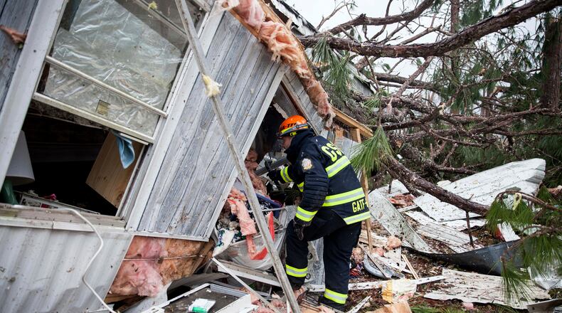 A rescue worker enters a hole in the back of a mobile home Monday, Jan. 23, 2017, in Big Pine Estates that was damaged by a tornado, in Albany, Ga. Fire and rescue crews were searching through the debris, looking for people who might have become trapped when the storm came through. (AP Photo/Branden Camp)