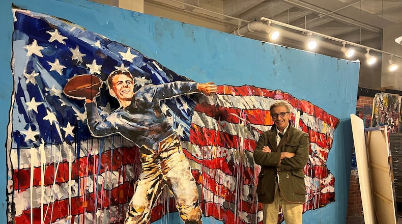 Artist Steve Penley stands in his Atlanta studio alongside recent paintings of Ronald Reagan and the American flag.