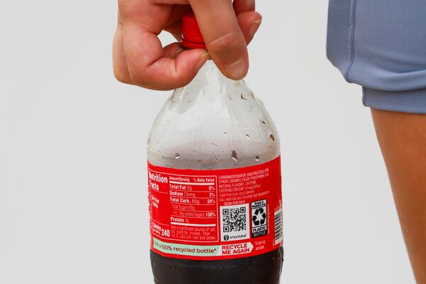 Delaney Britt Dutton of Brunswick, Georgia, holds a Cole bottle outside of the World of Coca-Cola in Atlanta on Saturday, July 19, 2025. President Trump recently declared that Coca-Cola will use cane sugar in its sodas rather than high-fructose corn syrup. (Abbey Cutrer / AJC)