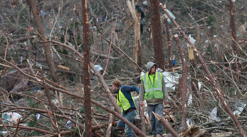 Two men searched through the debris along Lee Road 38 after a tornado struck Sunday in Beauregard. Curtis Compton/ccompton@ajc.com