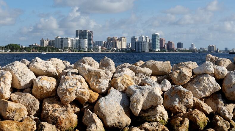 Limestone boulders meant to break up wave energy are stacked on a manmade island, part of the Palm Beach Resilient Island Project in the Tarpon Cove area near Lake Worth on July 1, 2022. Downtown West Palm Beach can be seen in the distance. The limestone will house oyster beds that naturally filter the water and abate nutrient pollution. (Amy Beth Bennett/South Florida Sun Sentinel/TNS)