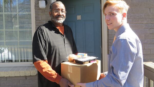 Marcel Lytle of Marietta receives his meal packages from Lincoln Wilson, 17, a volunteer with the Cobb Senior Services Meals on Wheels. PHOTO CREDIT: Laura Berrios