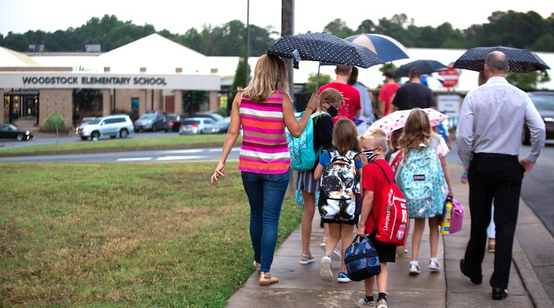 Parents walk their children to the entrance of Woodstock Elementary School on the first day of school on August 3, 2020. The Cherokee County School District reported 77% of its 42,000 students were physically back in their classrooms. STEVE SCHAEFER FOR THE ATLANTA JOURNAL-CONSTITUTION