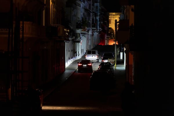 Vehicles navigate a dark street in Old San Juan, Puerto Rico, during an island-wide blackout, Wednesday, April 16, 2025. (AP Photo/Alejandro Granadillo)