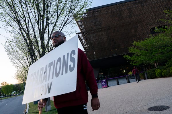 Pastor Robert Turner walks past the National Museum of African American History and Culture as part of his monthly walk from Baltimore to Washington to raise awareness of reparations on Wednesday, April 16, 2025, in Washington. (AP Photo/Nathan Howard)