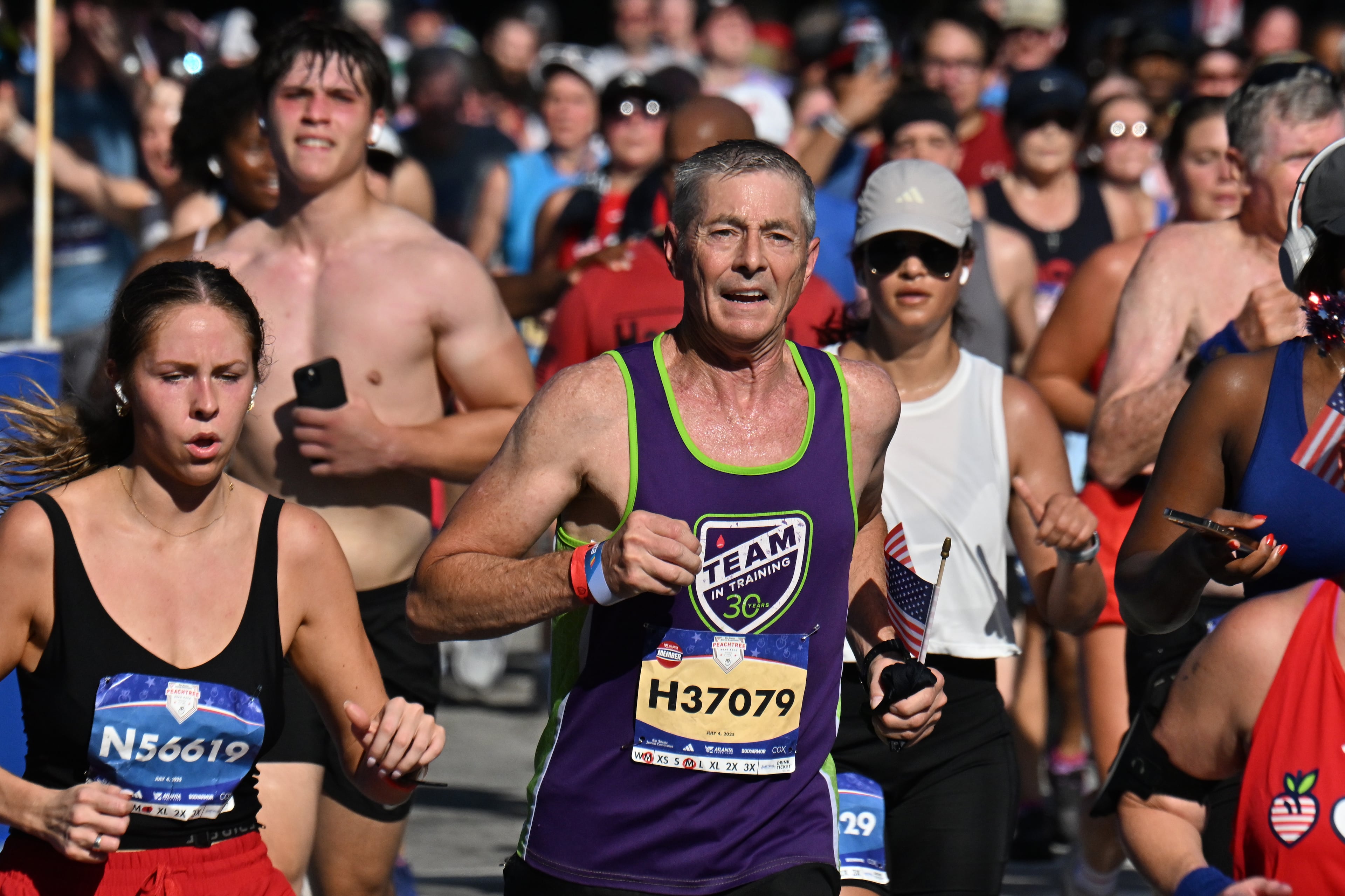 Runners cross the finish line during the 56th AJC Peachtree Road Race on Friday, July 4, 2025, in Atlanta. About 52,000 runners participated in the event. (Hyosub Shin/AJC)
