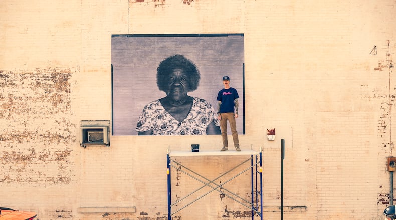 Photographer Raymond McCrea Jones with partially installed portrait of Betty E. Slaughter. The Palmetto Portrait Project documents one small town at a time of change for the city and the nation. Courtesy of Andrew Hetherington