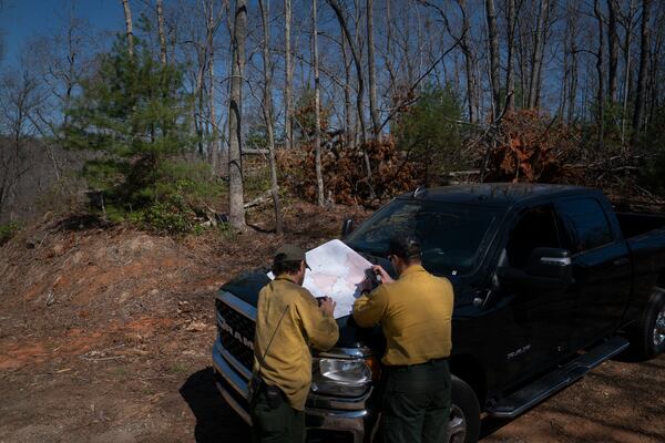Firefighters look at a map as the Black Cove Fire burns nearby Wednesday, March 26, 2025, in Saluda, N.C.. (AP Photo/Allison Joyce)