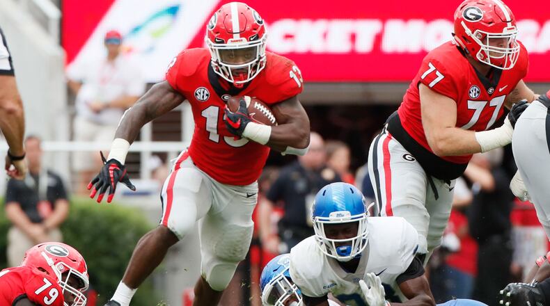 The Bulldogs offensive line supplies the daylight Saturdy and running back Elijah Holyfield makes the most of it. (BOB ANDRES  /BANDRES@AJC.COM)
