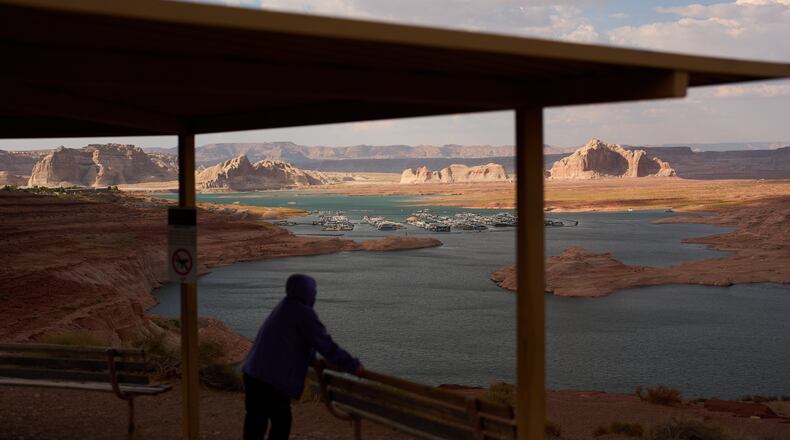 FILE - A person stands at an overlook near the Wahweap Marina on Lake Powell at the Glen Canyon National Recreation Area, July 15, 2026, near Page, Ariz. (AP Photo/John Locher, File)