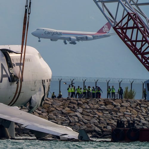 The wreckage of a cargo aircraft that skidded off a runway at the Hong Kong International Airport is prepared for removal on Sunday, Oct. 26, 2025. (AP Photo/Vernon Yuen)