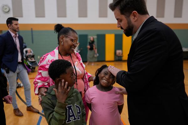 River Church Cincinnati pastor Cory Bowman, who is Vice President JD Vance's half brother and Cincinnati mayoral candidate, right, prays for healing over Ja'Sani Baltimore, 5, second from right, Kevon Winfield, 6, with Terra Williams during Easter worship service at the Hays Porter Elementary School gym Sunday, April 20, 2025, in Cincinnati. (AP Photo/Carolyn Kaster)