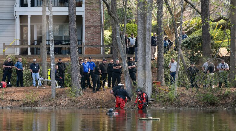Police and fire department personnel from multiple agencies stand along a pond in Gwinnett County on Friday as they searched for a missing 5-year-old boy.