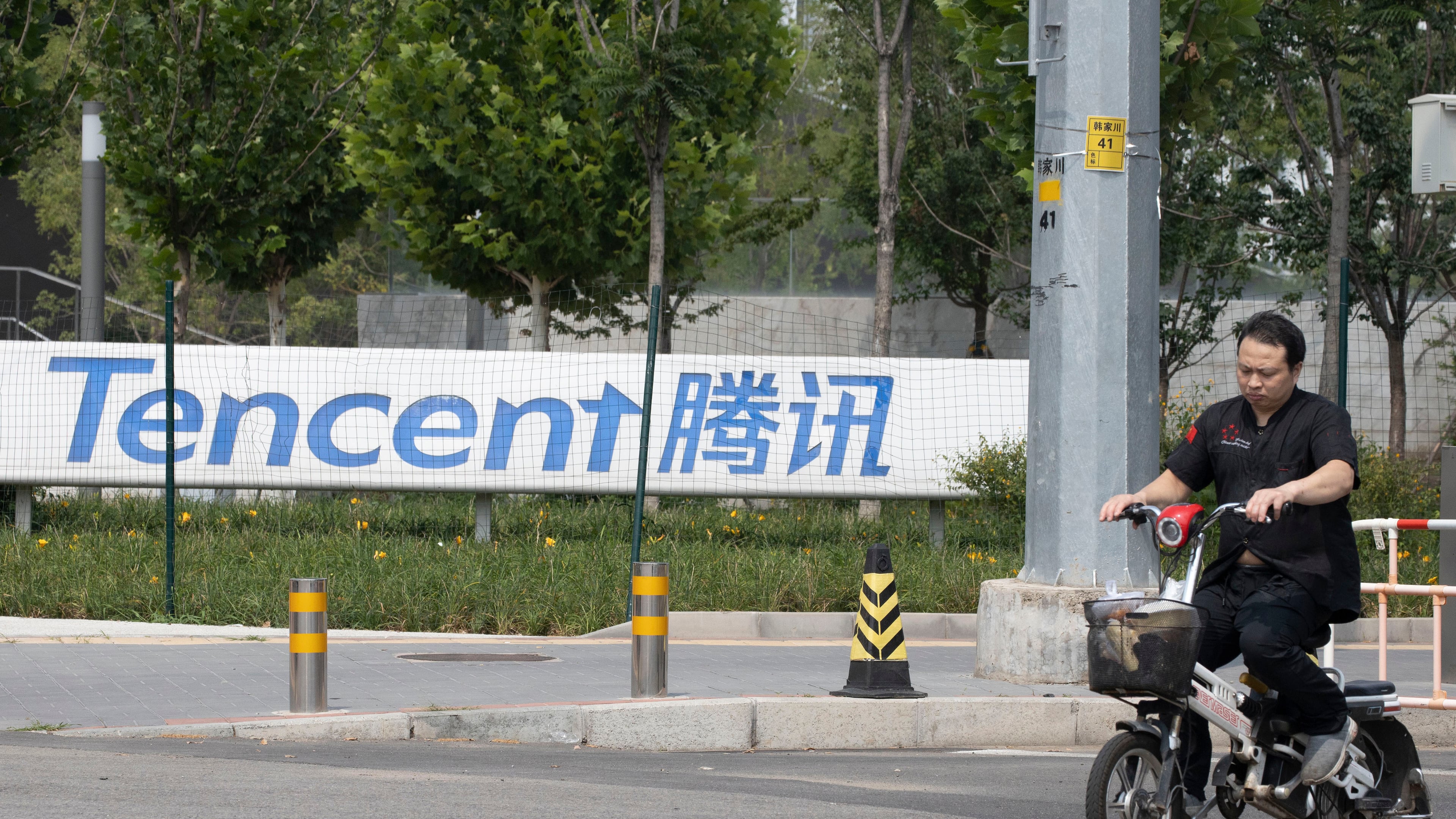 FILE - A man rides past the Tencent headquarters in Beijing, China on Aug. 7, 2020. (AP Photo/Ng Han Guan, File)