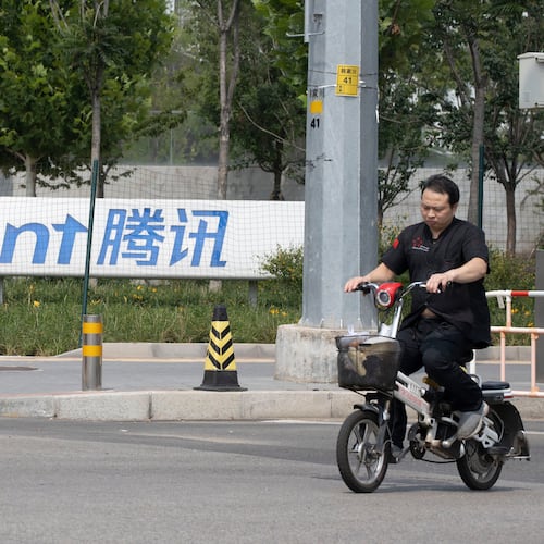FILE - A man rides past the Tencent headquarters in Beijing, China on Aug. 7, 2020. (AP Photo/Ng Han Guan, File)