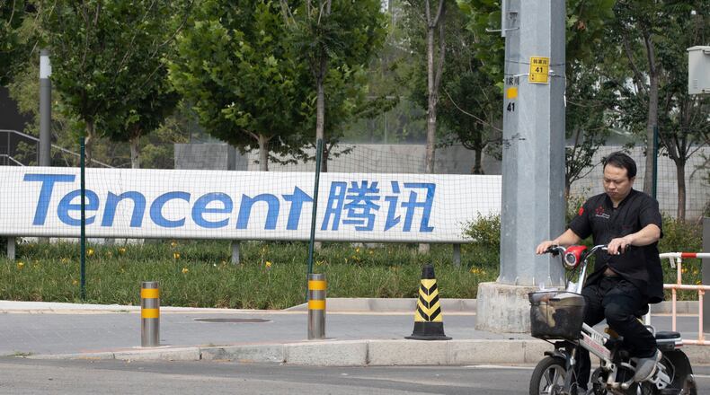 FILE - A man rides past the Tencent headquarters in Beijing, China on Aug. 7, 2020. (AP Photo/Ng Han Guan, File)