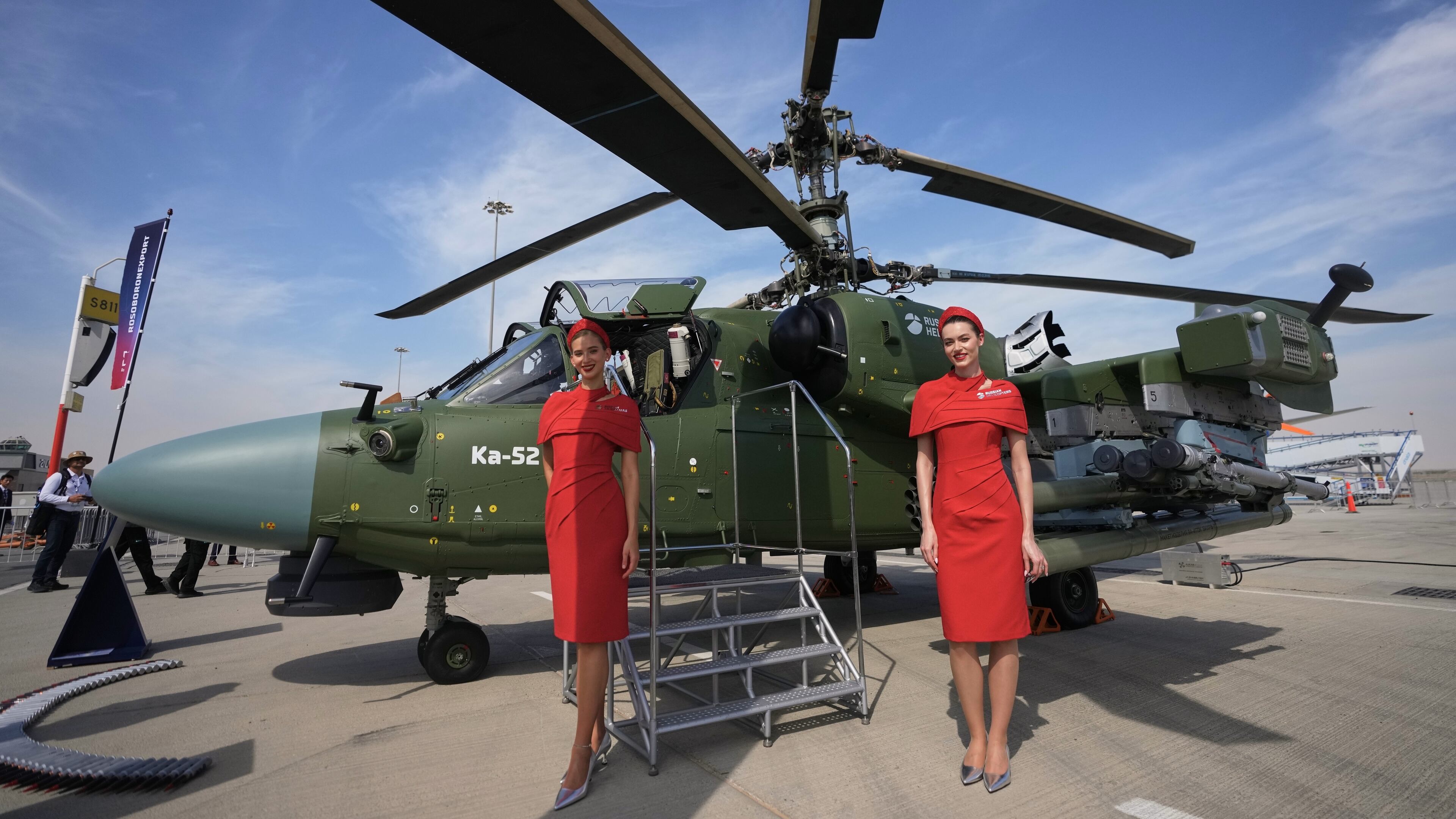 Russian hostesses stand by a Russian KA-52 attack helicopter at the Dubai Air Show in Dubai, United Arab Emirates, Monday, Nov. 17, 2025. (AP Photo/ Fatima Shbair)