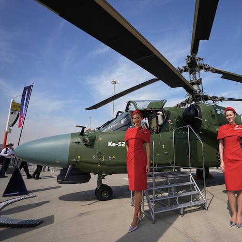 Russian hostesses stand by a Russian KA-52 attack helicopter at the Dubai Air Show in Dubai, United Arab Emirates, Monday, Nov. 17, 2025. (AP Photo/ Fatima Shbair)