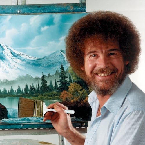 In this undated photo provided by Bob Ross Inc., Bob Ross poses for a photo in front of one of his paintings. (Bob Ross Inc. via AP)