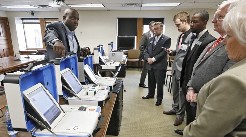 Dwayne Broxton, left, a regional sales director for Hart InterCivic, demonstrates his company’s voting machines to lawmakers on the second day of this year’s General Assembly session. Bob Andres / bandres@ajc.com