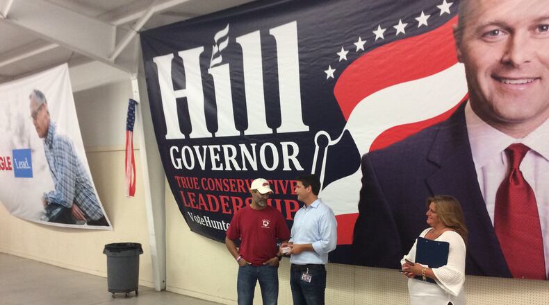 State Sen. Mike Williams, a candidate for governor, chats with a potential supporter beneath the gaze of two mamoth banners from rivals Casey Cagle and Hunter Hill. Jim Galloway, jgalloway@ajc.com