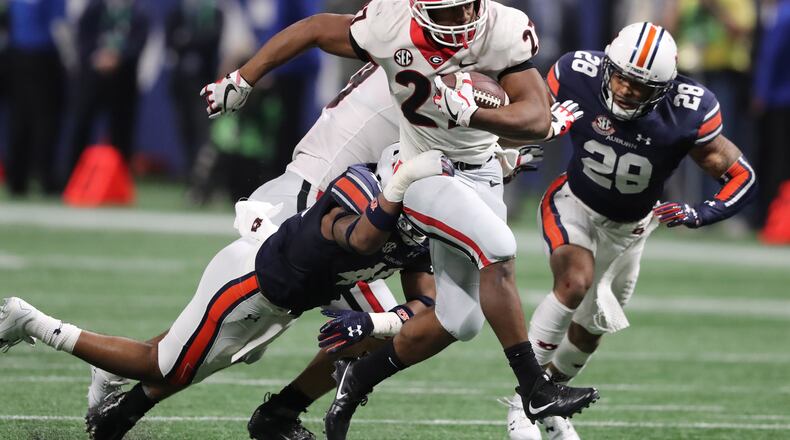Nick Chubb high-steps past Auburn defenders Darrell Williams (l) and Tray Matthews (28) during the second half of the SEC Championshipgame Saturday.