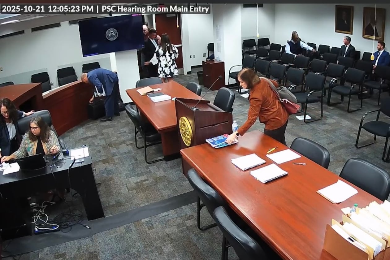 A screengrab from video taken inside the Georgia Public Service Commission hearing room shows former PSC candidate Patty Durand appearing to pick up a copy of allegedly trade-secret information belonging to Georgia Power. The video later shows Durand put what police say was a different copy of a Georgia Power booklet into her purse and leave the room during a recess in a hearing on Tuesday, Oct. 21, 2025. Durand has been charged with theft of trade secrets, records show. The AJC obtained the video from the Public Service Commission through a Georgia Open Records Act request.