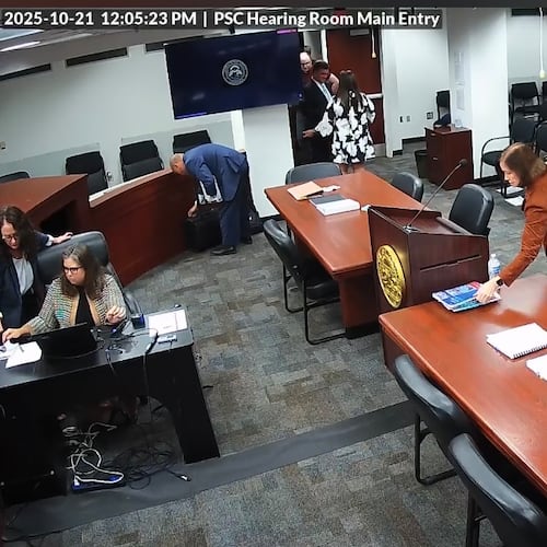A screengrab from video taken inside the Georgia Public Service Commission hearing room shows former PSC candidate Patty Durand appearing to pick up a copy of allegedly trade-secret information belonging to Georgia Power. The video later shows Durand put what police say was a different copy of a Georgia Power booklet into her purse and leave the room during a recess in a hearing on Tuesday, Oct. 21, 2025. Durand has been charged with theft of trade secrets, records show. The AJC obtained the video from the Public Service Commission through a Georgia Open Records Act request.