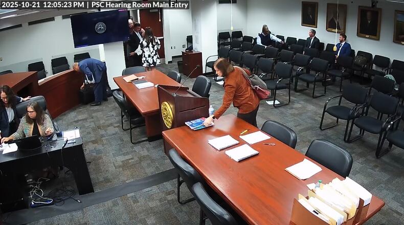 A screengrab from video taken inside the Georgia Public Service Commission hearing room shows former PSC candidate Patty Durand appearing to pick up a copy of allegedly trade-secret information belonging to Georgia Power. The video later shows Durand put what police say was a different copy of a Georgia Power booklet into her purse and leave the room during a recess in a hearing on Tuesday, Oct. 21, 2025. Durand has been charged with theft of trade secrets, records show. The AJC obtained the video from the Public Service Commission through a Georgia Open Records Act request.