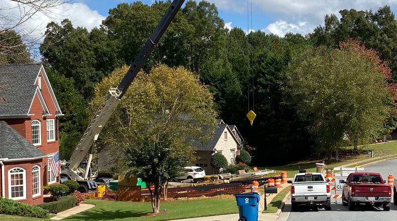 Suwanee is performing emergency repairs to pipe on Ruby Forest Parkway that has failed causing a sinkhole that is threatening an adjacent home. (Karen Huppertz for the AJC)
