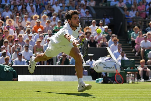 Spain's Carlos Alcaraz returns to Taylor Fritz of the U.S. in a men's singles semifinal at the Wimbledon Tennis Championships in London, Friday, July 11, 2025. (AP Photo/Kin Cheung)