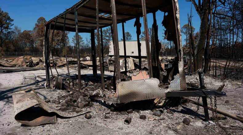 A burned trailer sits near a destroyed home as the Brantley Highway 82 fire burns, Thursday, April 23, 2026, near Nahunta, Ga. (AP Photo/Mike Stewart)