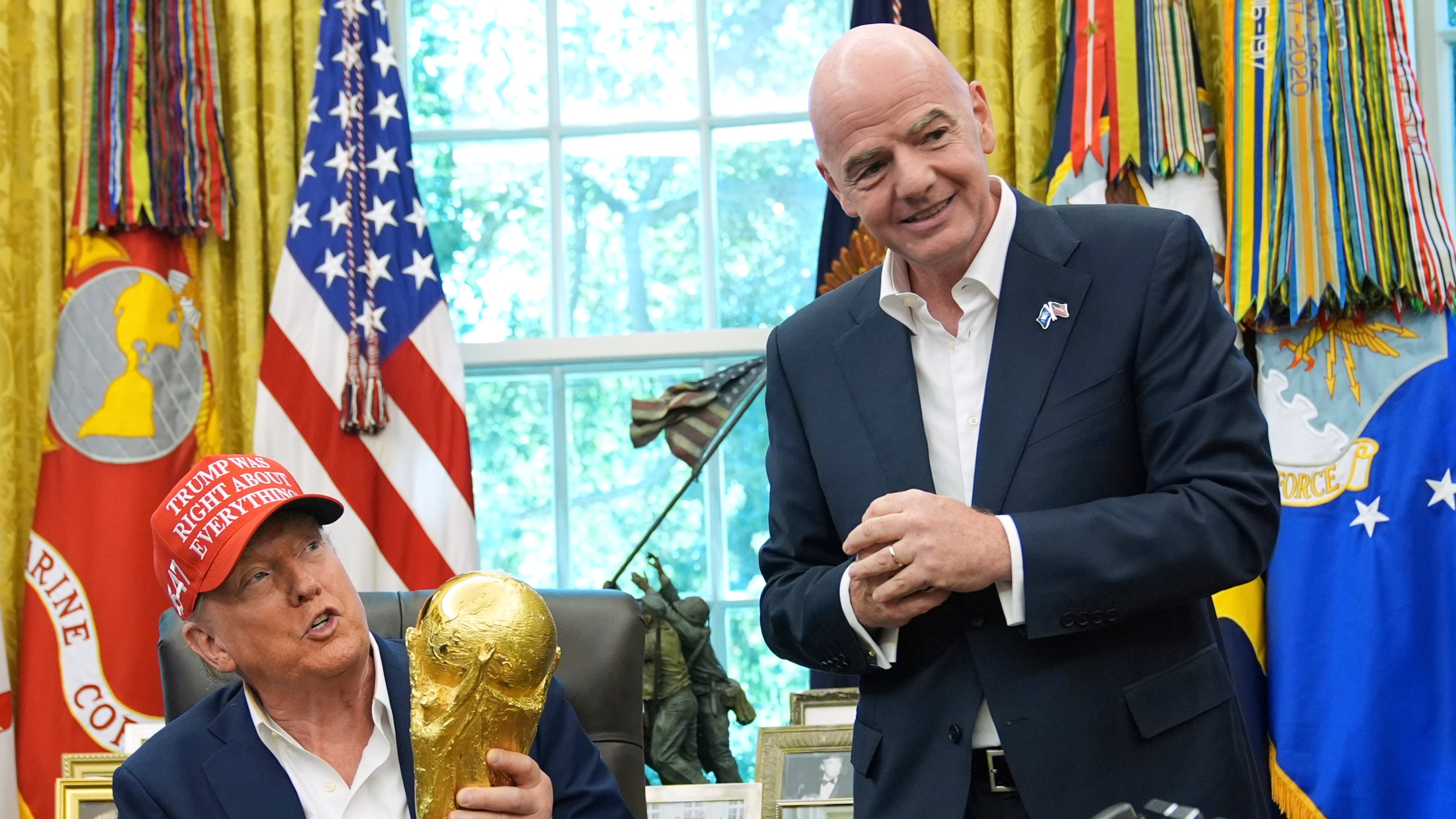 FILE - President Donald Trump holds the FIFA World Cup Winners Trophy as FIFA President Gianni Infantino looks on during an announcement in the Oval Office of the White House, Aug. 22, 2025, in Washington. (AP Photo/Jacquelyn Martin, File)