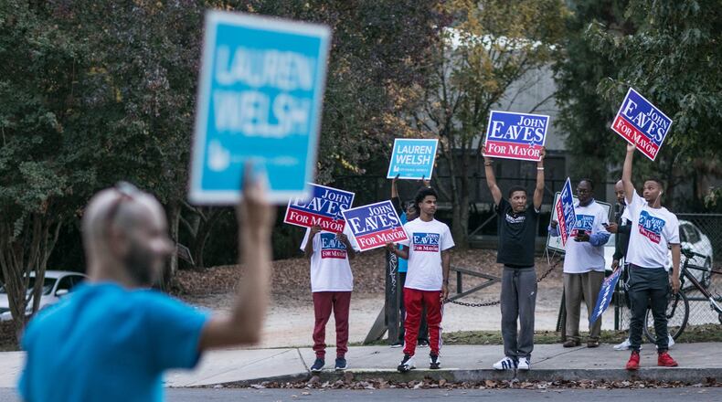 People hold campaign signs outside of a voting precinct on 10th Street in downtown on Election Day in Atlanta. BRANDEN CAMP/SPECIAL